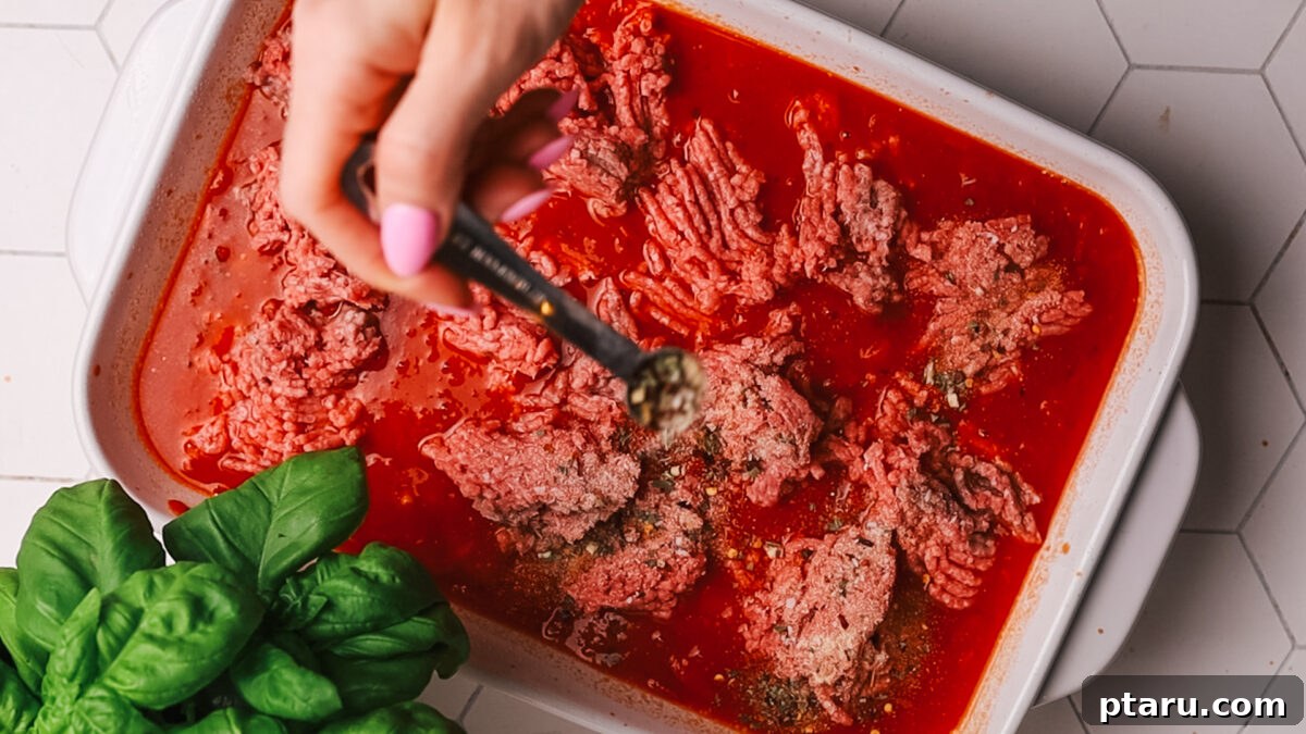 Classic Comfort Hamburger Bake 7 The ground beef layer being seasoned with a mix of spices, including garlic powder, onion powder, and Italian seasoning.