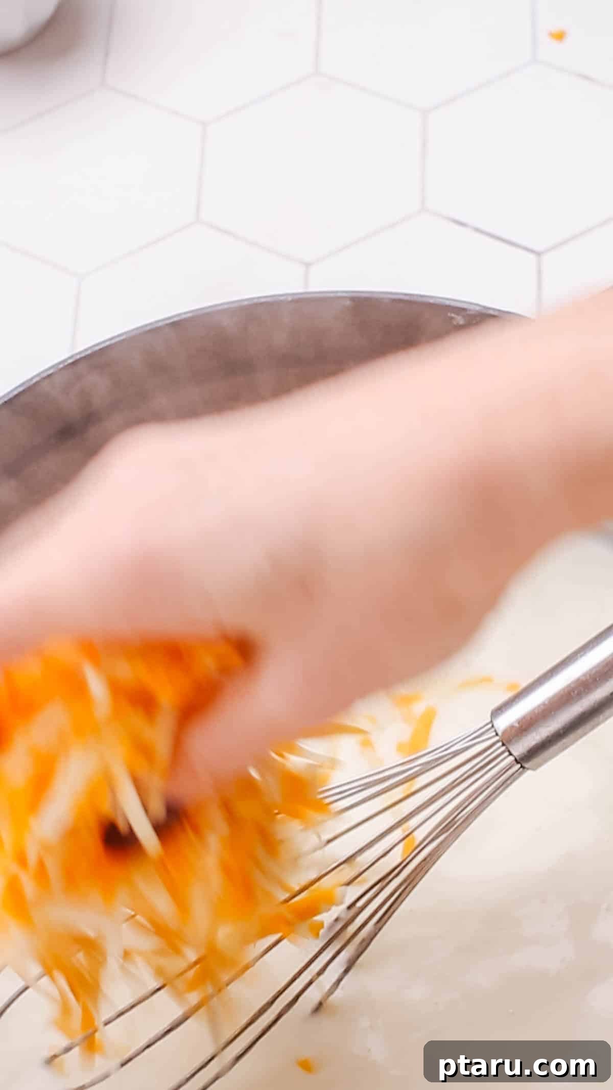 Game-Changing Cauliflower Casserole 5 Adding grated cheddar cheese to a creamy white sauce in a saucepan, stirring until melted and smooth for a cheesy macaroni and cheese base.
