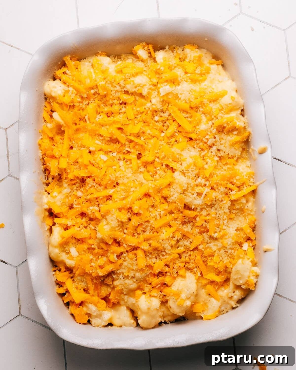 Game-Changing Cauliflower Casserole 10 A close-up view of a cauliflower casserole generously topped with a mixture of panko breadcrumbs and shredded cheddar cheese, ready for baking.