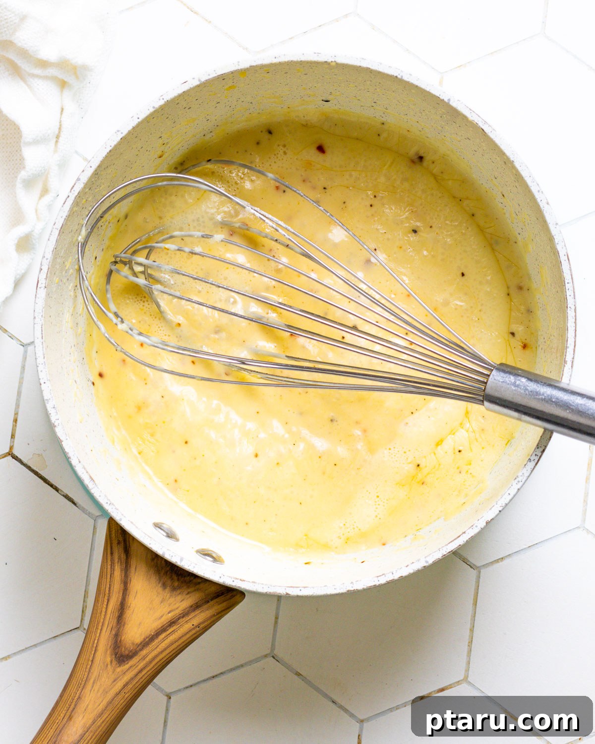 Creamy Garlic Parmesan Sauce 4 A whisk stirring garlic parmesan sauce in a saucepan.