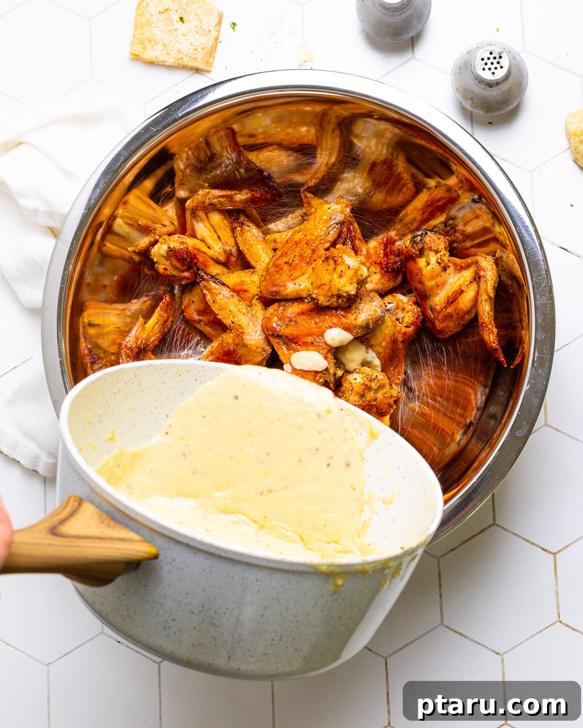 Creamy Garlic Parmesan Sauce 5 Pouring garlic parmesan sauce over crispy chicken wings.