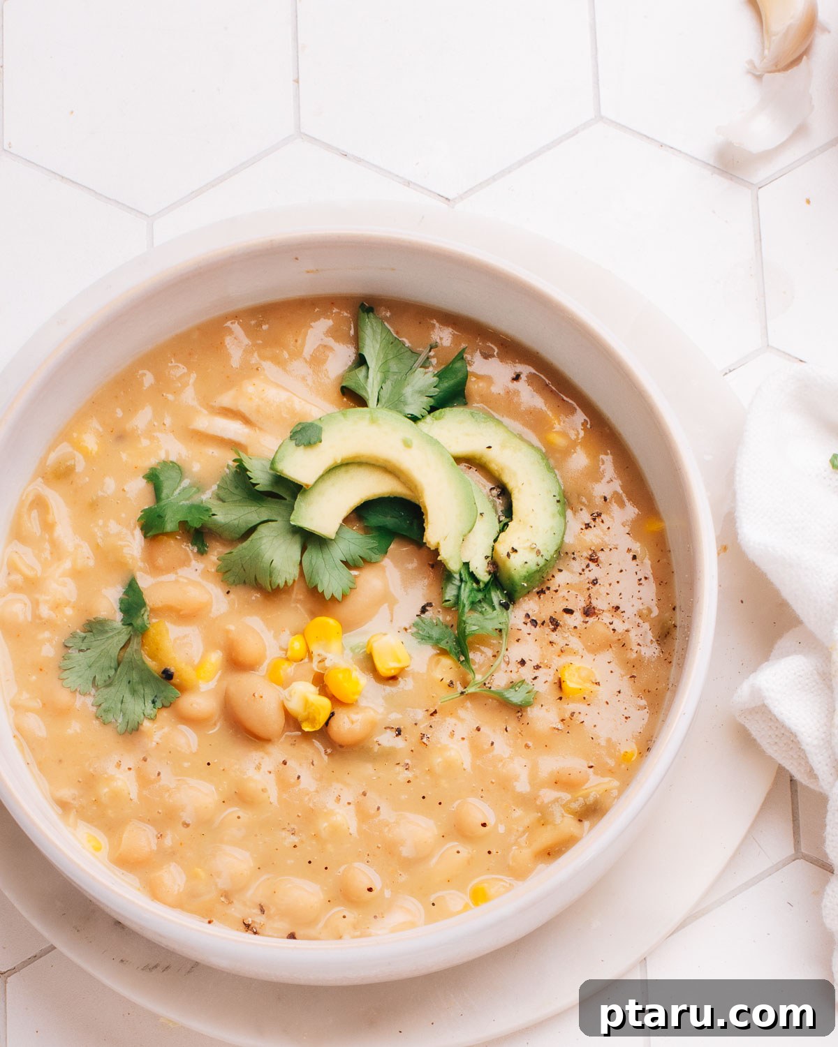 Hearty Turkey White Bean Chili 2 White bean turkey chili topped with fresh corn, vibrant cilantro, and creamy avocado slices in a rustic bowl.