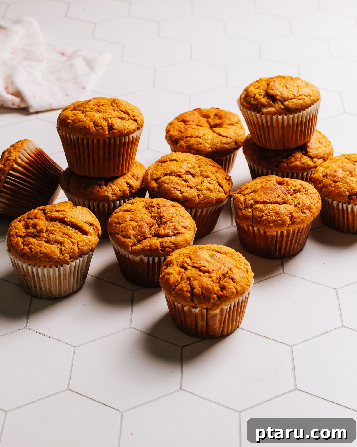 Spiced Pumpkin Banana Muffins 2 Soft, fluffy Pumpkin Banana Muffins on a white countertop, ready to be enjoyed.
