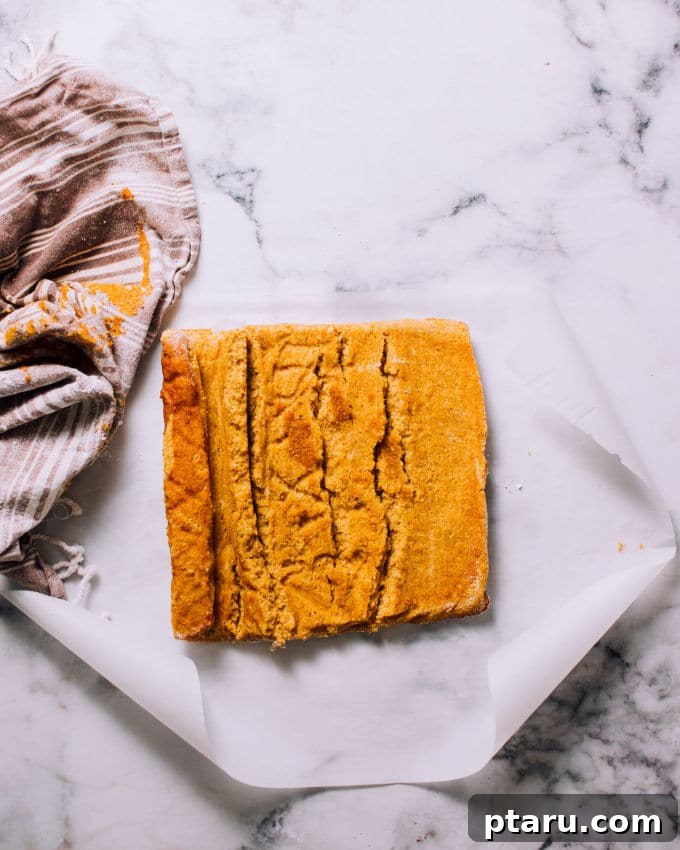 Spiced Pumpkin Swirl Cake 3 Pumpkin roll cake batter spread evenly on a parchment-lined baking sheet, ready for the oven