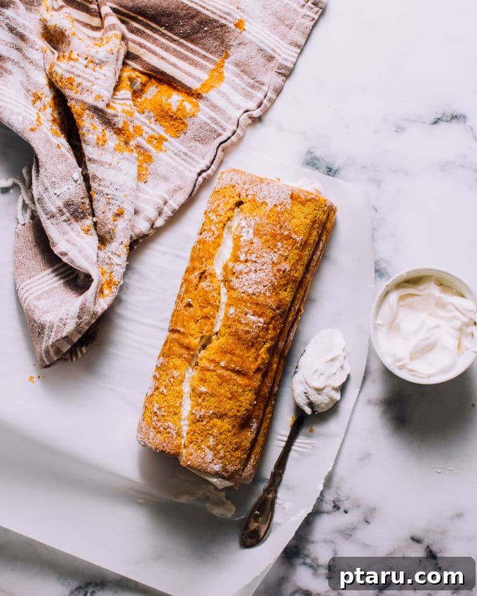 Spiced Pumpkin Swirl Cake 6 Creamy, fluffy cream cheese filling being spread generously over the unrolled pumpkin cake