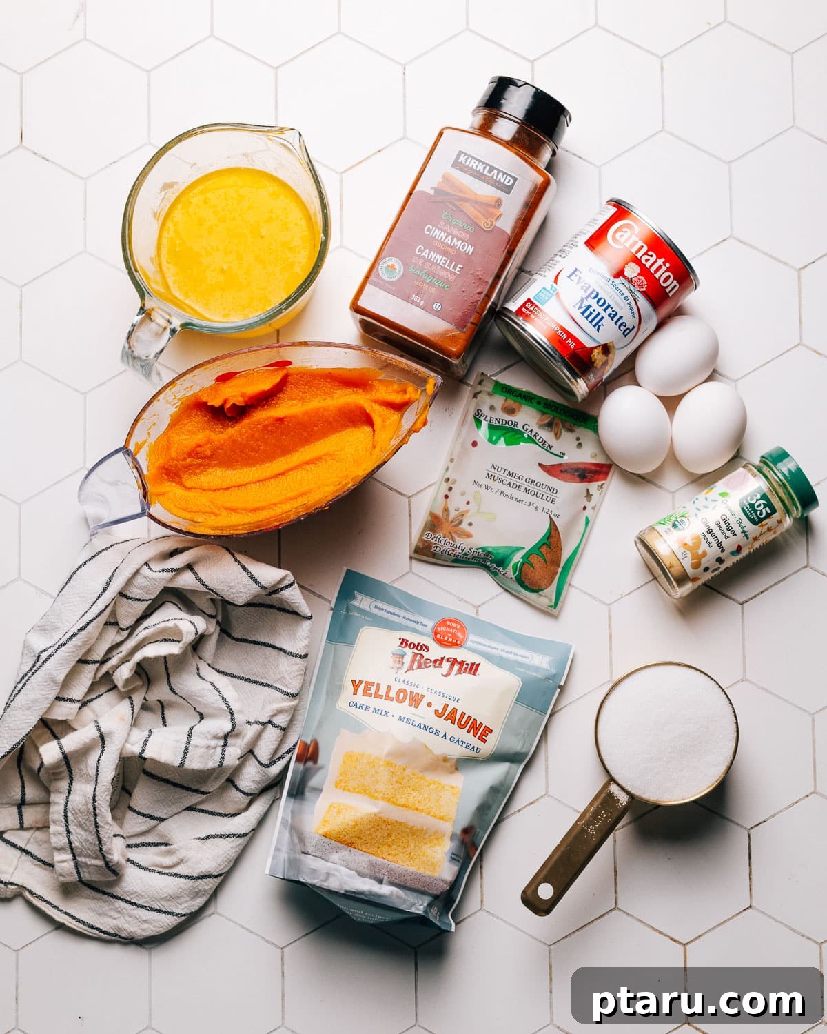 Effortless Autumn Pumpkin Bake 3 Collection of Pumpkin Dump Cake ingredients laid out on a kitchen counter, featuring pumpkin puree, evaporated milk, eggs, sugar, spices, cake mix, and butter.