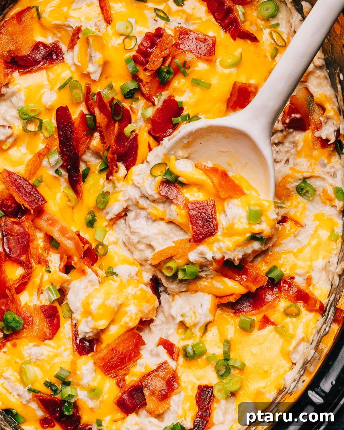 Seriously Addictive Ranch Chicken 2 Crack Chicken in slow cooker with a spoon, ready to be served.