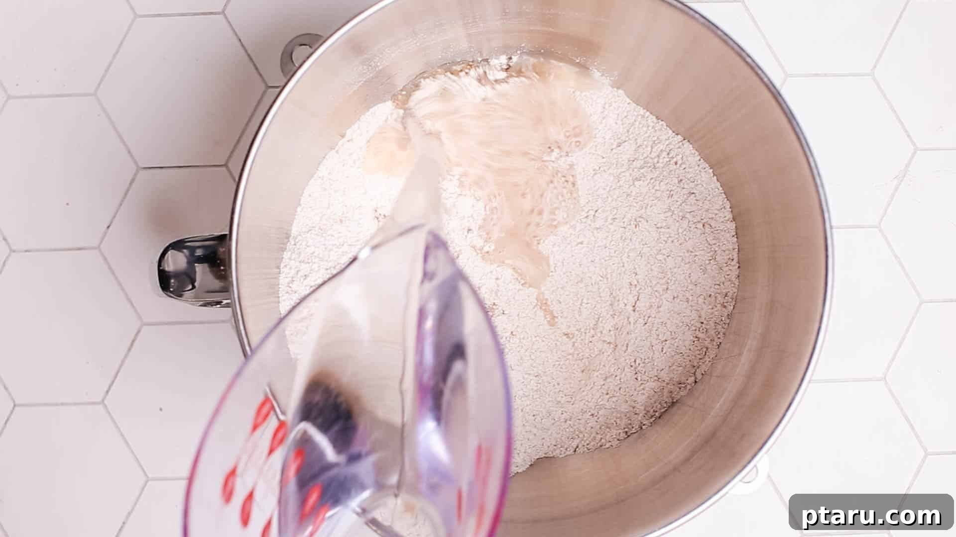 Effortless Artisan Dutch Oven Bread 4 A person adding water to a bowl of flour, illustrating the mixing process for no-knead bread.