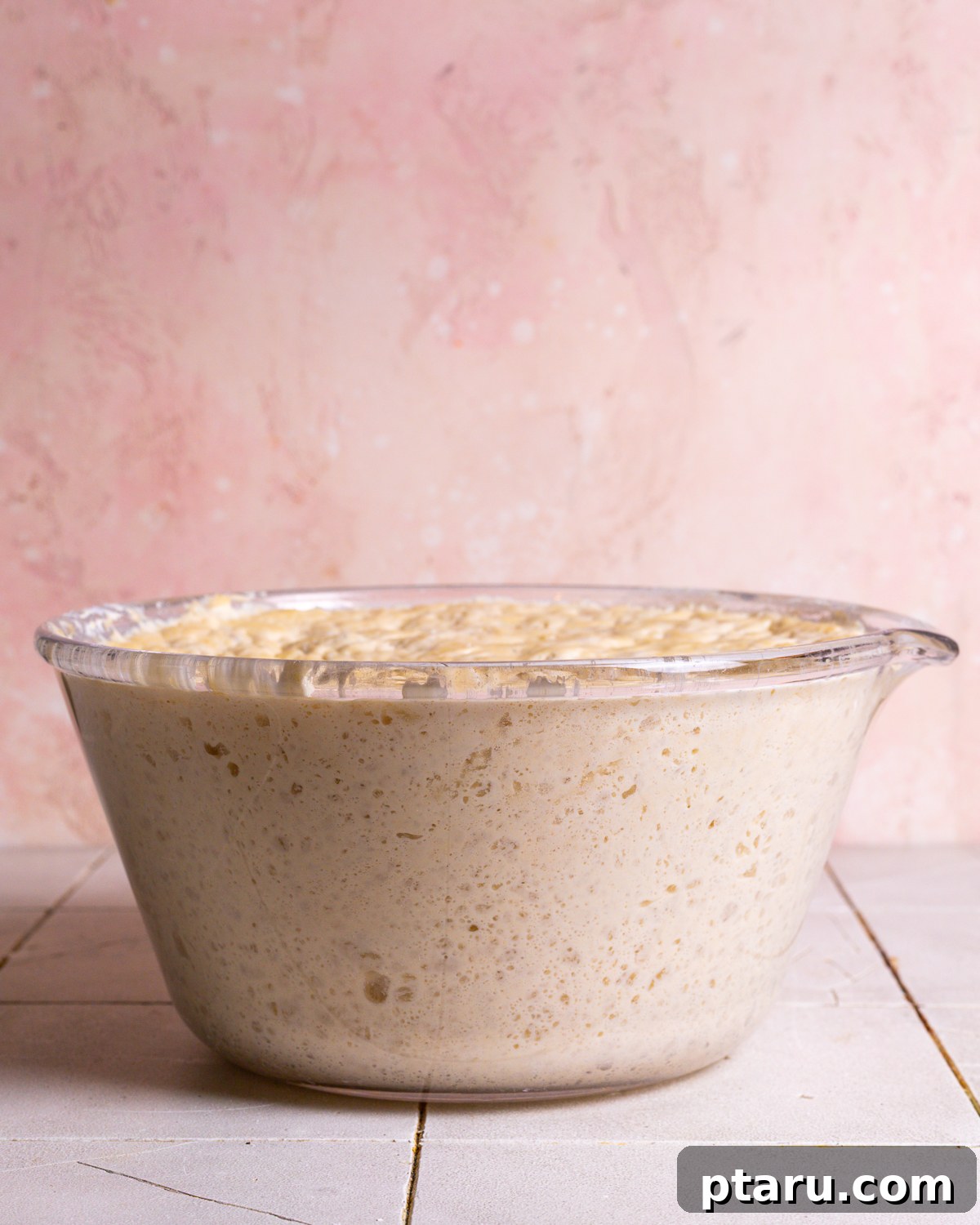 Effortless Artisan Dutch Oven Bread 5 A bowl of no-knead bread dough after rising, showing its bubbly and expanded texture.