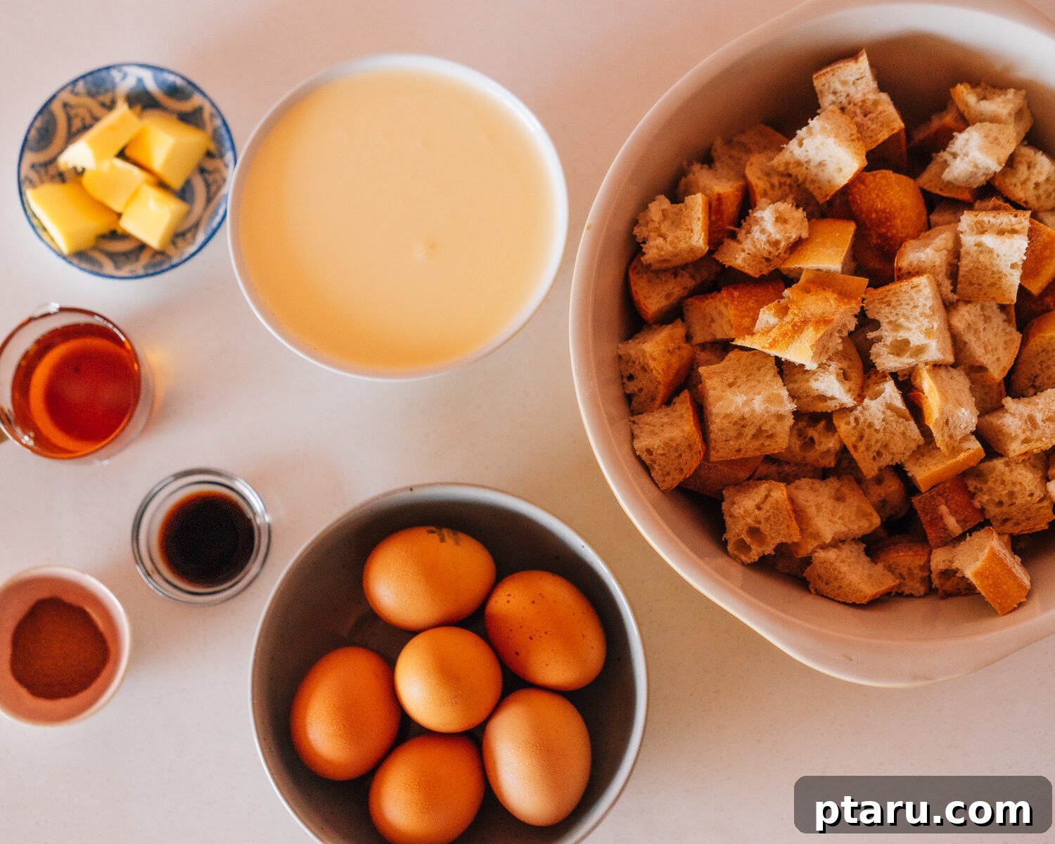 Overnight French Toast Bake for Easy Mornings 3 A selection of fresh ingredients laid out for a French toast casserole recipe: bread, eggs, milk, cream, vanilla, cinnamon, and salt.