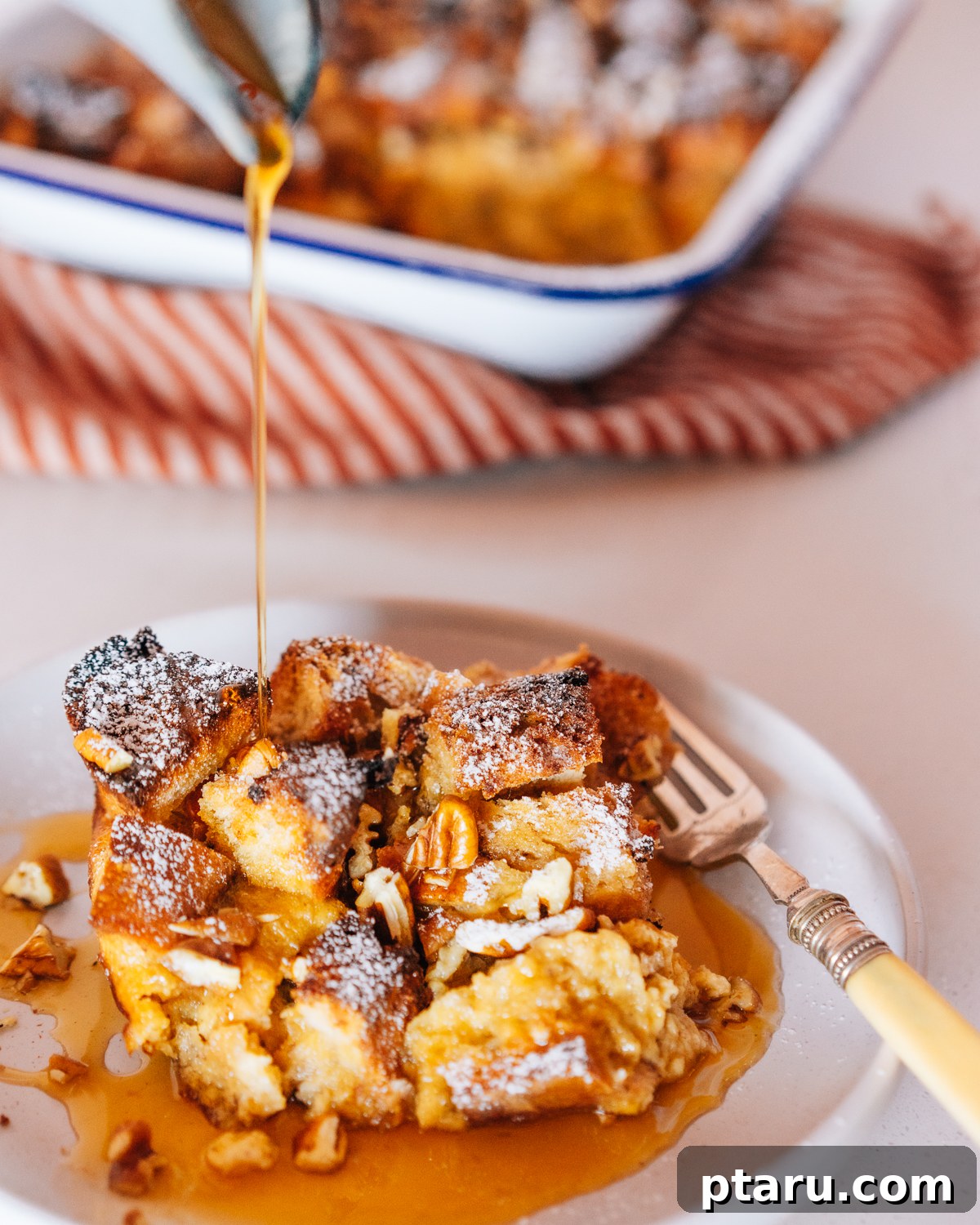 Overnight French Toast Bake for Easy Mornings 7 A slice of golden French Toast Casserole on a plate, garnished with powdered sugar and berries.