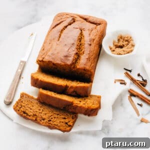 Several slices of tender pumpkin bread artfully arranged on a sheet of parchment paper, invitingly displaying its rich texture and moist crumb.