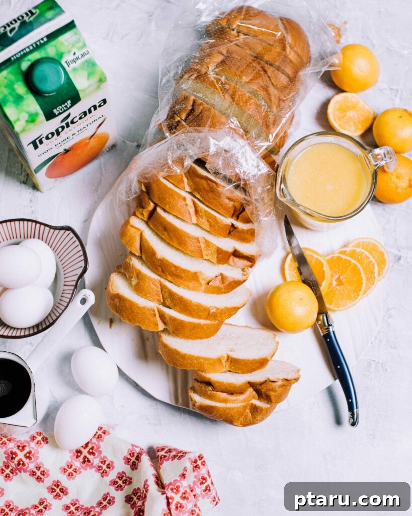 Provençal Orange Bake 3 A collection of ingredients for Orange French Toast Casserole, including neatly cubed day-old bread, vibrant orange zest, fresh eggs, heavy cream, and natural orange juice, laid out on a clean surface.