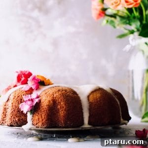 An orange pound cake with orange glaze, ready to be sliced and served.