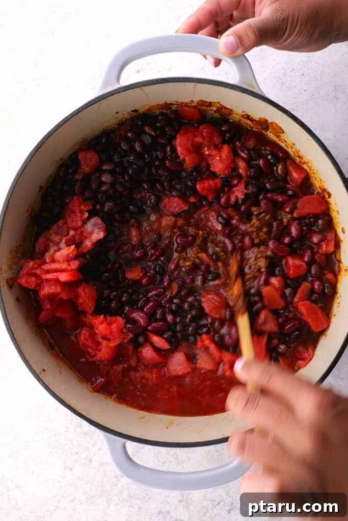 Ultimate Chili Con Carne 7 Step 4: Stirring tomato paste into the browned beef, allowing it to toast and darken.