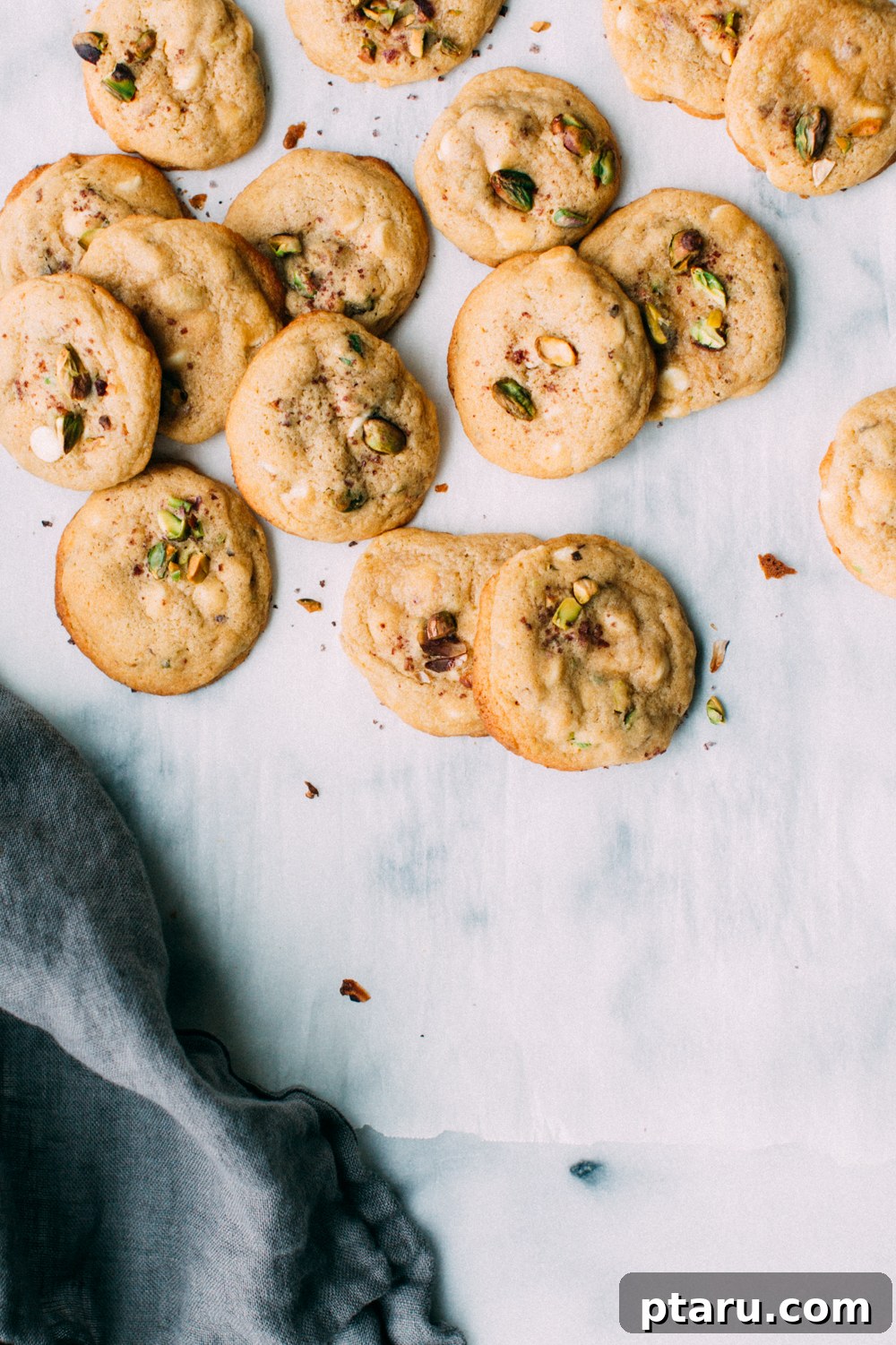 Zesty Lemon Pistachio White Chocolate Delights 2 Close-up of freshly baked Lemon Pistachio White Chocolate Cookies on a cooling rack, showcasing their golden edges and creamy white chocolate chips.
