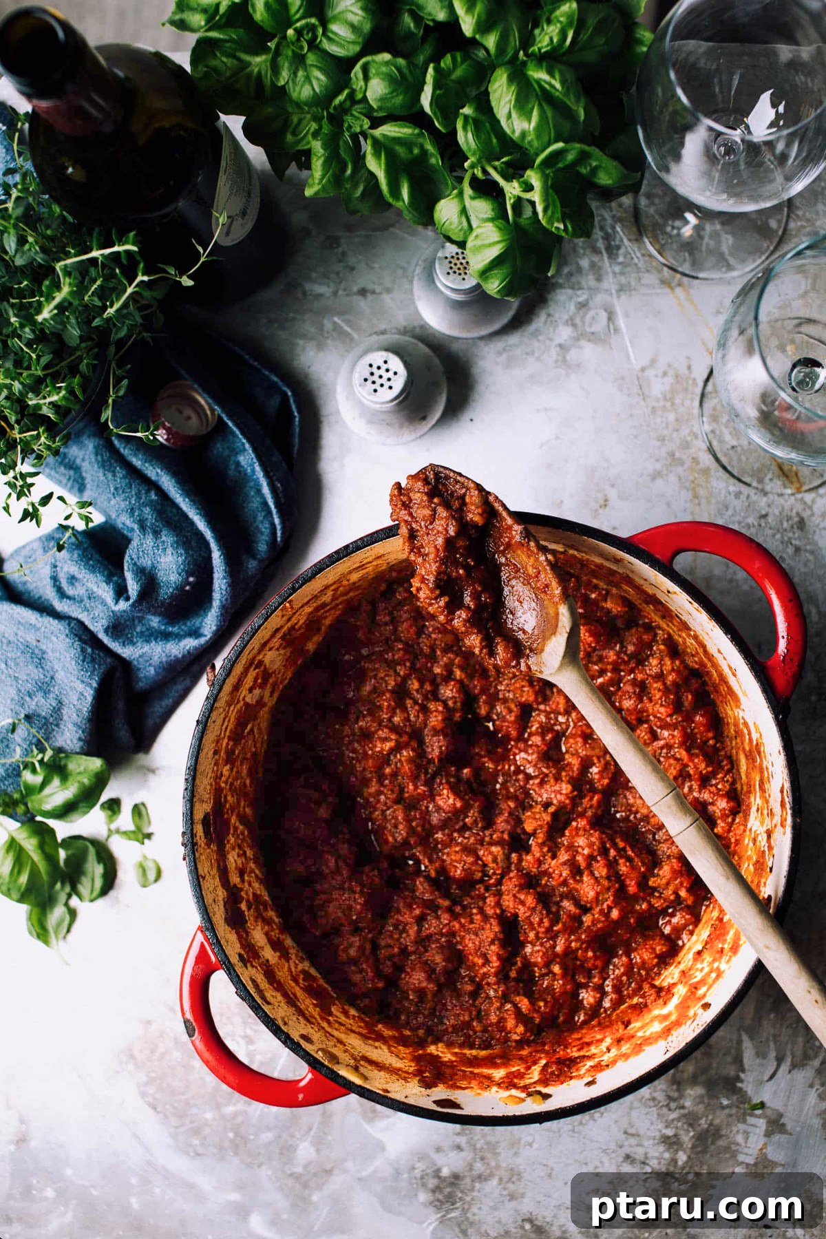 Ultimate Rich and Easy Meat Sauce 2 A big pot of meat sauce with fresh herbs and a blue napkin.