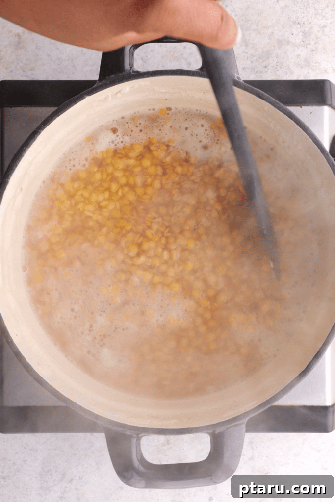 Spiced Masoor Dal Curry 4 Cooking red lentils in a pot on the stovetop.