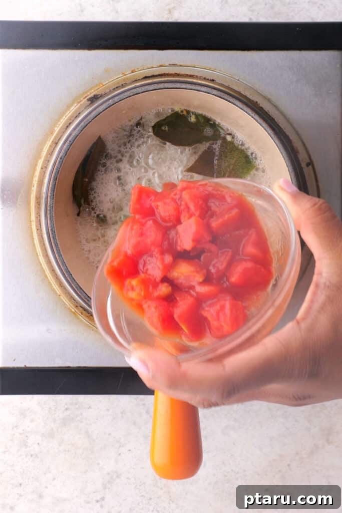 Spiced Masoor Dal Curry 6 Adding diced tomatoes to the sizzling dal tadka in a small pan.