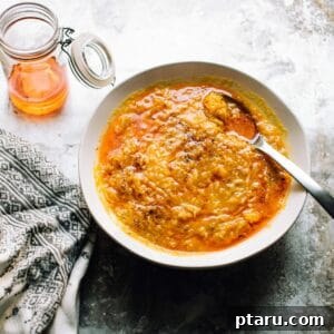 A bowl of rich pumpkin soup with ginger, rice, and a drizzle of chili oil.