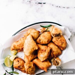 Crispy Chicken Samosas 10 Chicken Samosas on a plate with one cut open.