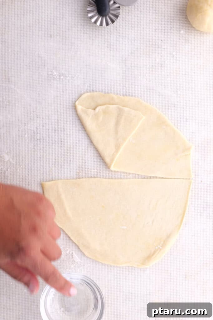 Crispy Chicken Samosas 5 Cutting the flattened dough in half to create half-moon shapes for samosas.