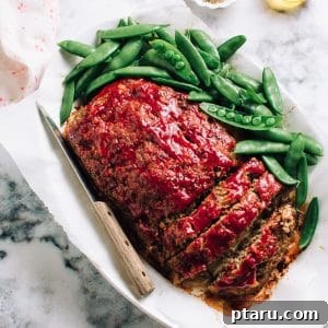The best meatloaf, sliced on a plate with snap peas.