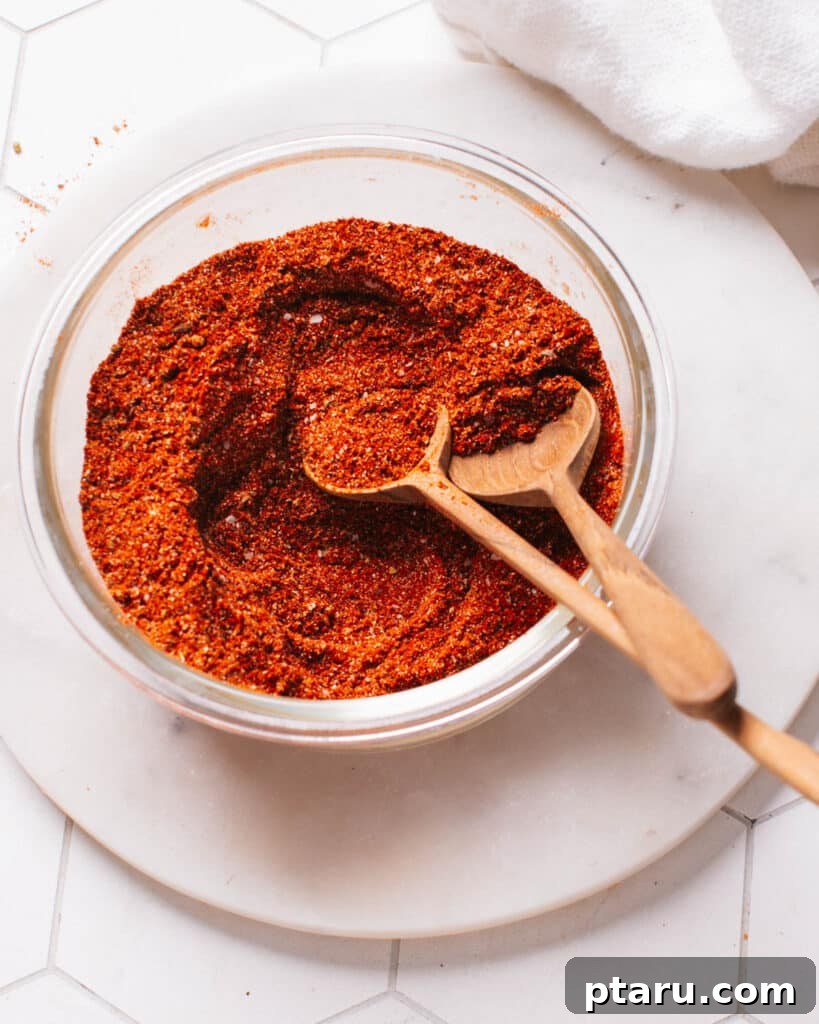 Authentic Mexican Ground Beef Tacos 5 Homemade chili seasoning blend in a glass container with spoons for measurement.
