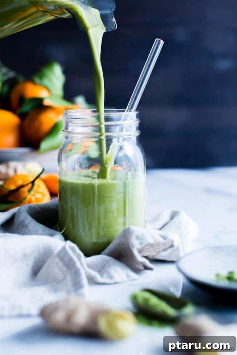 25+ Game-Changing Healthy Smoothie Recipes 2 Freshly blended green smoothie being poured into a glass, with vibrant oranges in the background, signaling a healthy and zesty flavor profile.