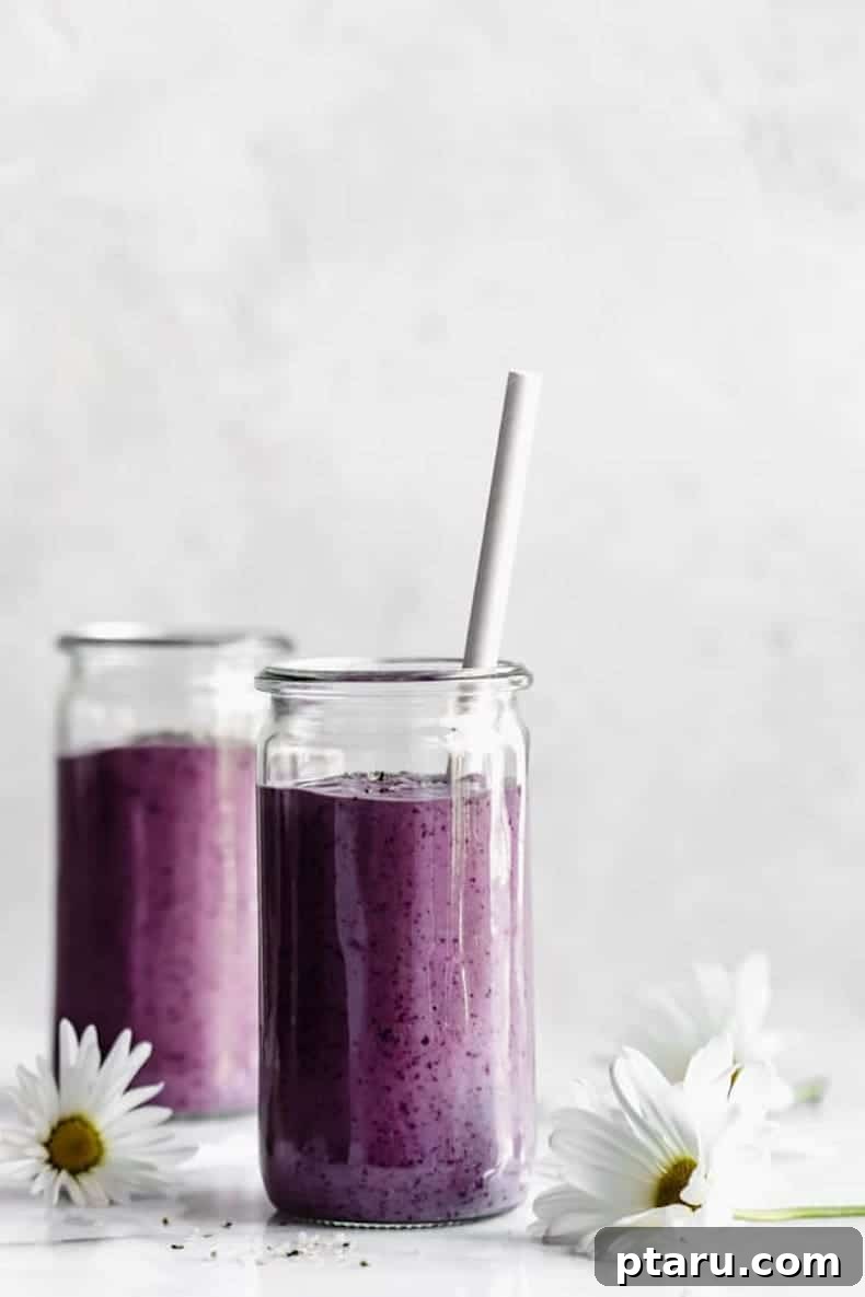 25+ Game-Changing Healthy Smoothie Recipes 18 A vibrant blueberry avocado smoothie beautifully presented on a marble backdrop, with a fresh daisy adding a touch of natural charm, highlighting a healthy and flavorful blend.