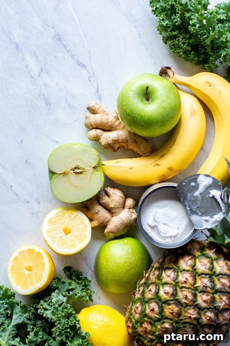 25+ Game-Changing Healthy Smoothie Recipes 19 A colorful flat lay featuring green apple, ginger, lemon, banana, and pineapple on a marble backdrop, representing fresh and vibrant ingredients for a tropical green smoothie.