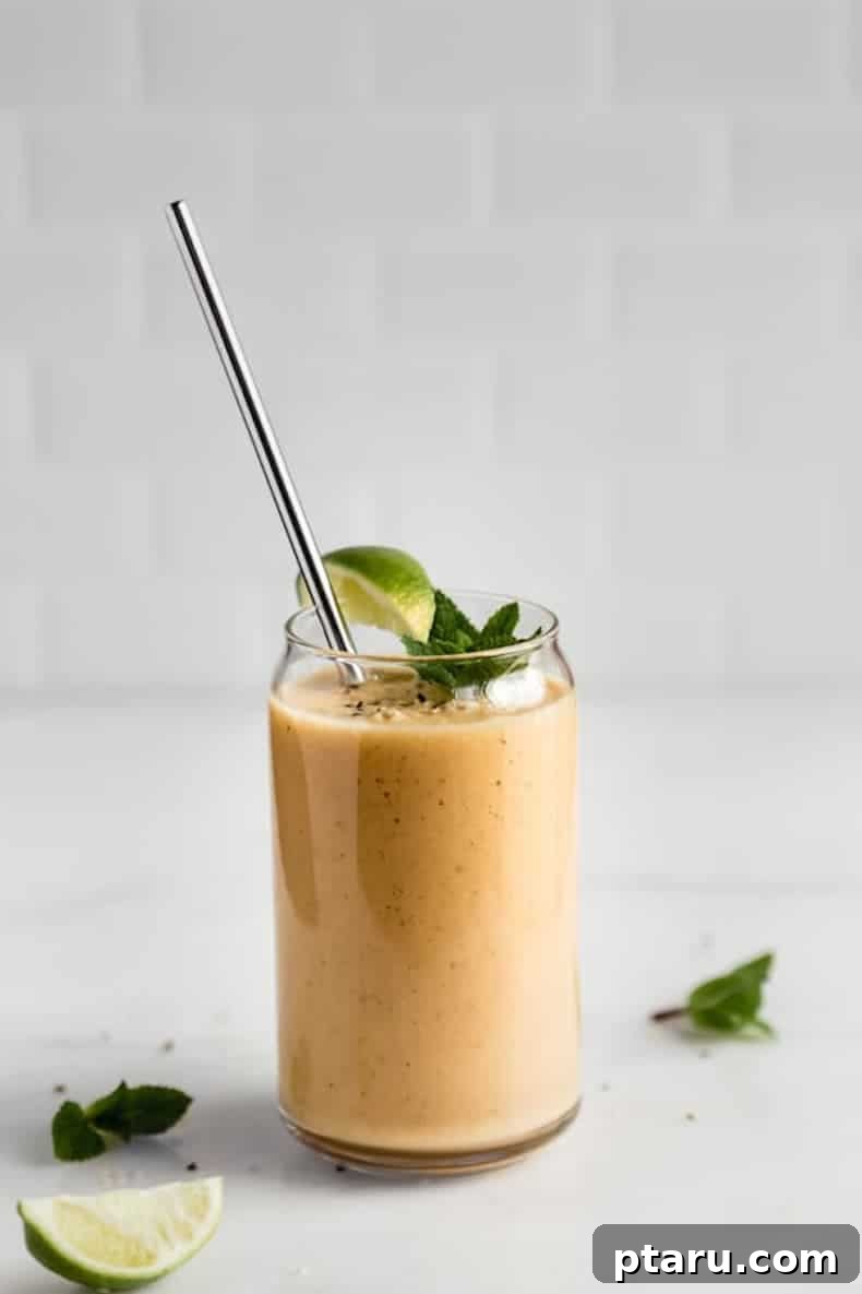 25+ Game-Changing Healthy Smoothie Recipes 20 A vibrant orange smoothie served in a glass with a straw and a sprig of mint on a table, suggesting a refreshing tropical mojito flavor.