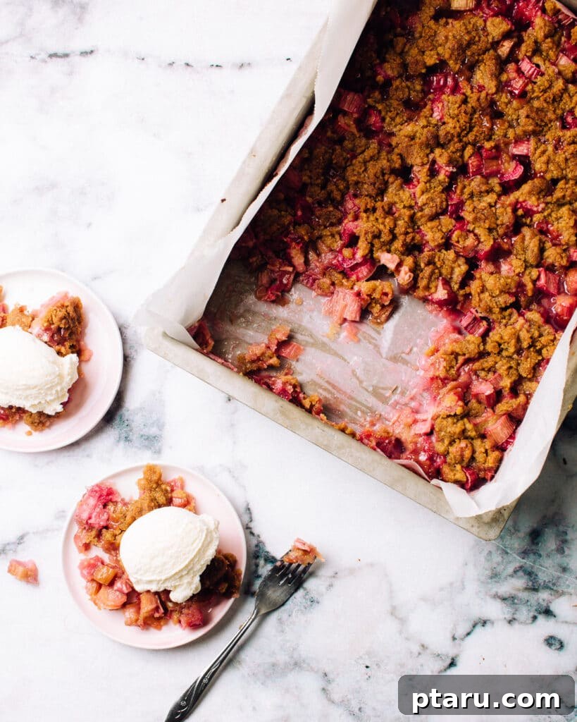 Homestyle Rhubarb Crisp 4 A pan of easy rhubarb crisp, freshly baked and served with scoops of vanilla ice cream on plates.