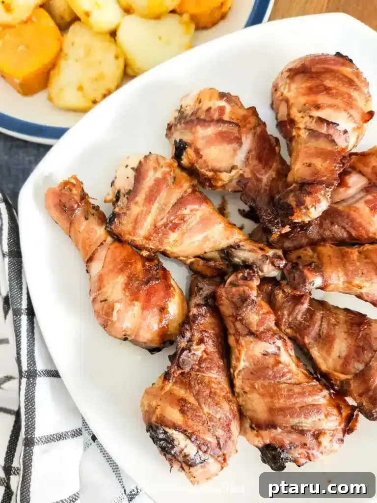 41 Succulent Chicken Drumstick Recipes You Can Make Effortlessly 20 Appetizing Oven-Baked Bacon Wrapped Drumsticks served on a plate.