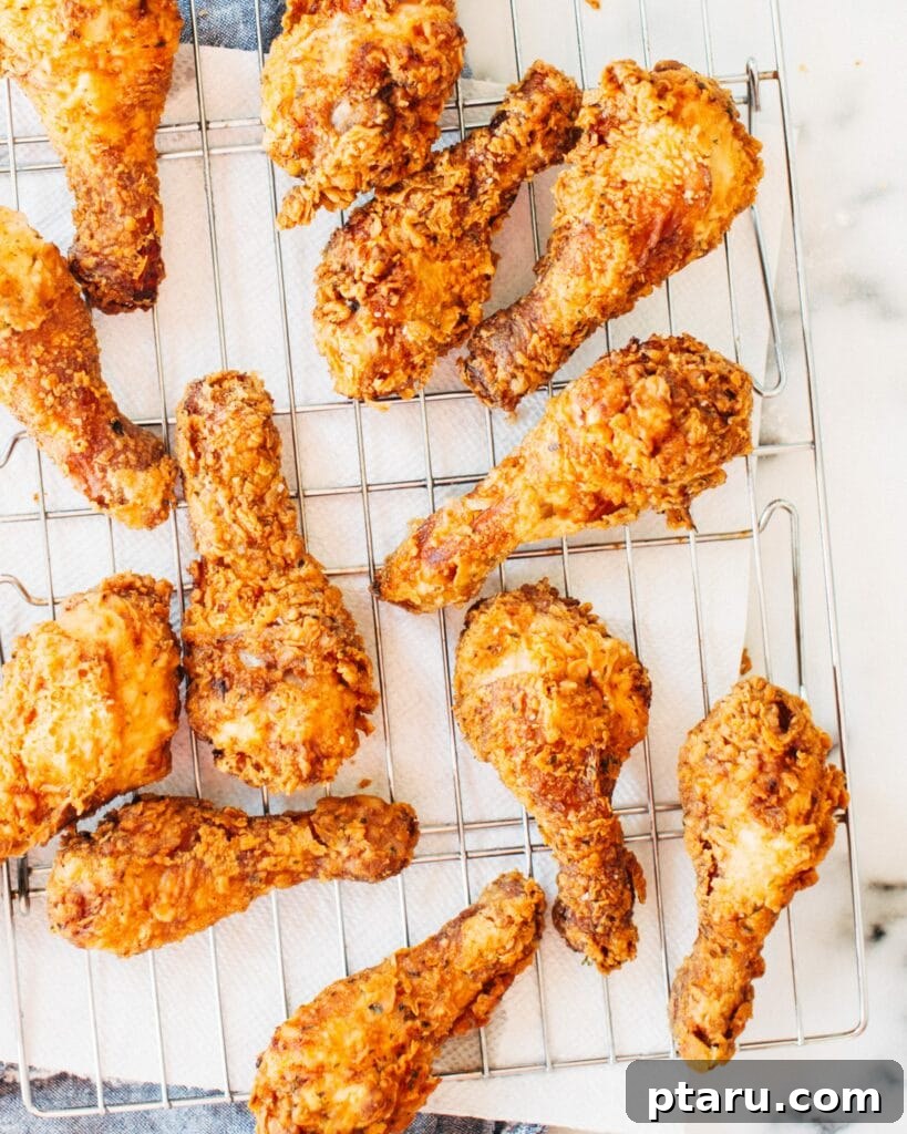 41 Succulent Chicken Drumstick Recipes You Can Make Effortlessly 4 Perfectly golden-brown Crispy Buttermilk Fried Chicken drumsticks resting on a wire rack.