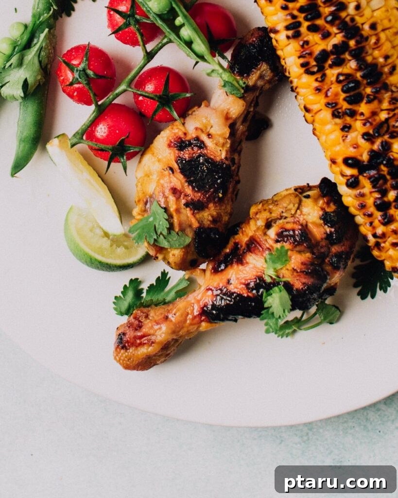 41 Succulent Chicken Drumstick Recipes You Can Make Effortlessly 5 Garlic & Lime Grilled Chicken drumsticks served on a plate with grilled corn, cherry tomatoes, and lime wedges.