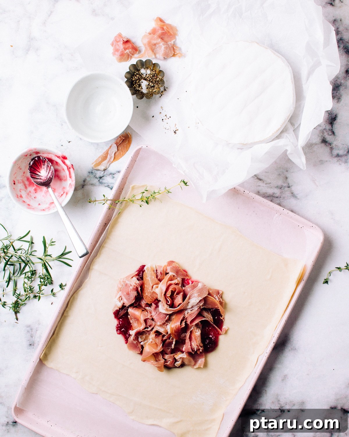 Golden Puff Pastry Brie with Prosciutto and Cranberry 5 Layering torn Prosciutto di Parma over cranberry sauce.