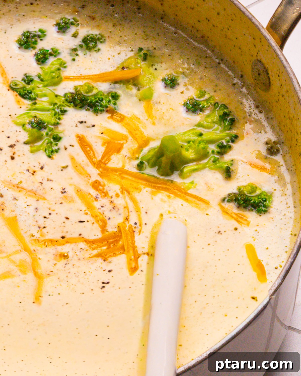 Fifteen Flavors Defining 2025 12 Broccoli Cheddar Soup bubbling in a pot with a spoon, ready to serve.