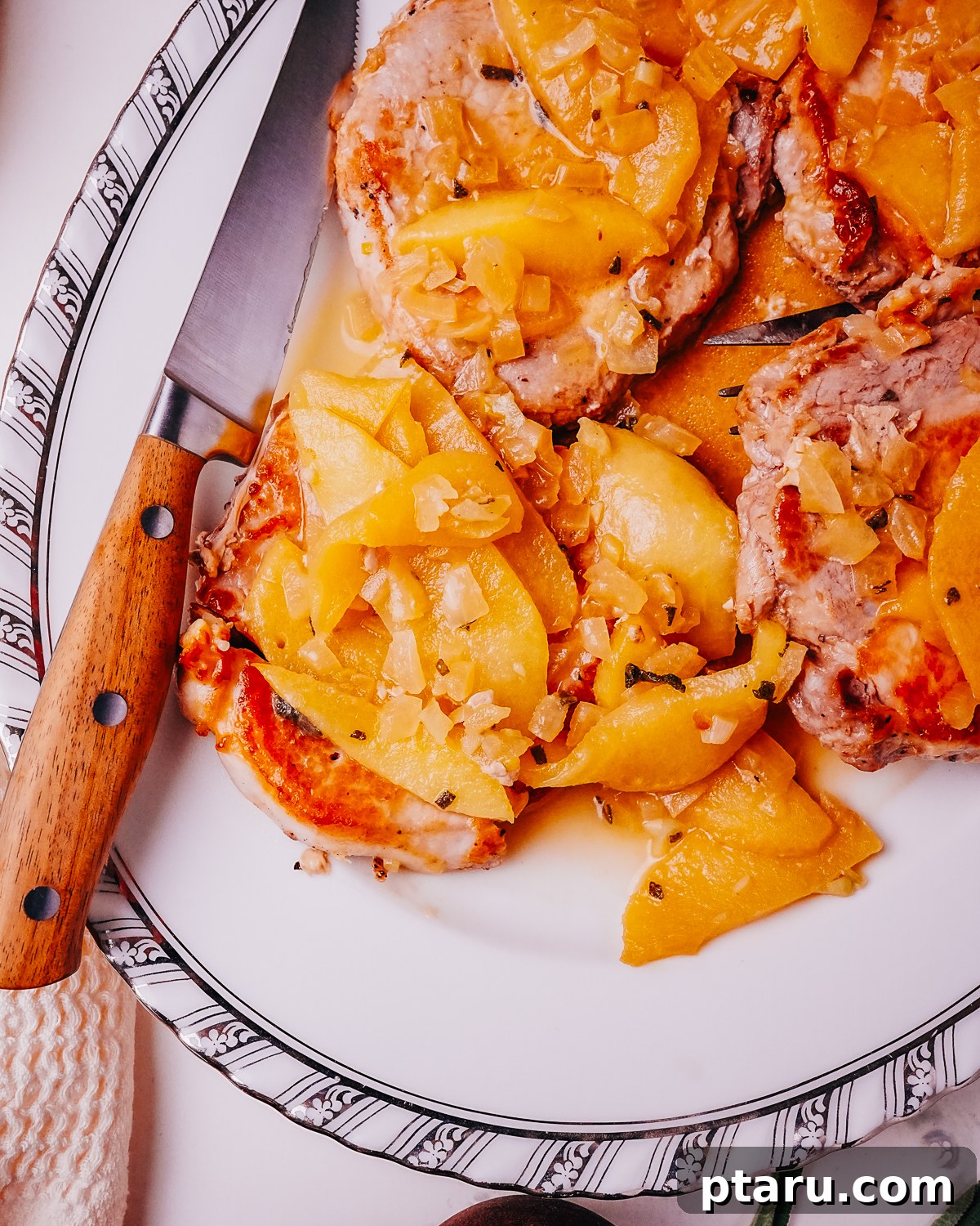 Caramelized Apple Pork Chops with Savory Sauce 2 Pork Chops with Apples on a plate with a knife and fork, showcasing a perfect slice of tender pork and caramelized apples.