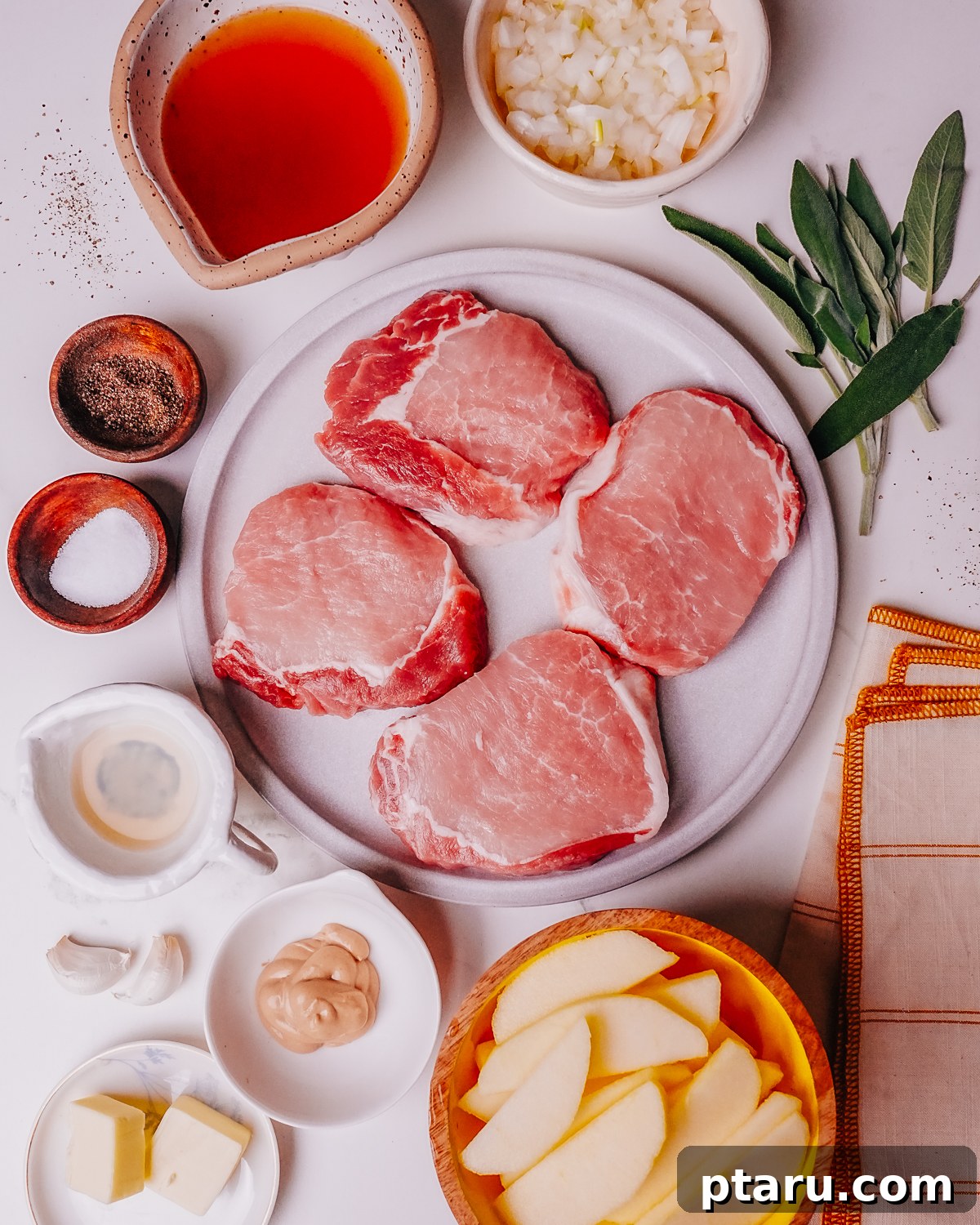 Caramelized Apple Pork Chops with Savory Sauce 3 All the fresh ingredients for Pork Chops with Apples laid out on a cutting board, including apples, onions, pork chops, and herbs.