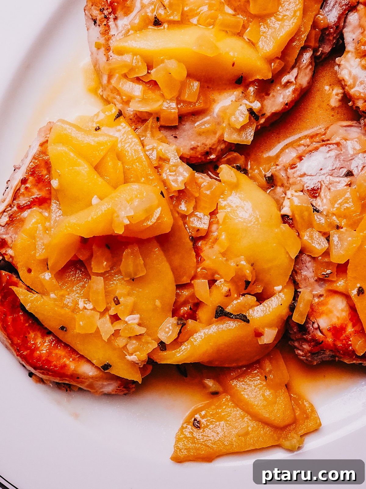 Caramelized Apple Pork Chops with Savory Sauce 10 A close-up view of the finished Pork Chops with Apples, garnished with fresh sage, highlighting the glossy sauce and tender apples.