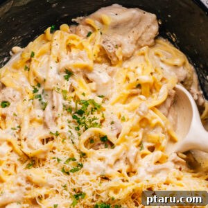 Crockpot Chicken Alfredo recipe close up shot with a spoon, highlighting the creamy texture.