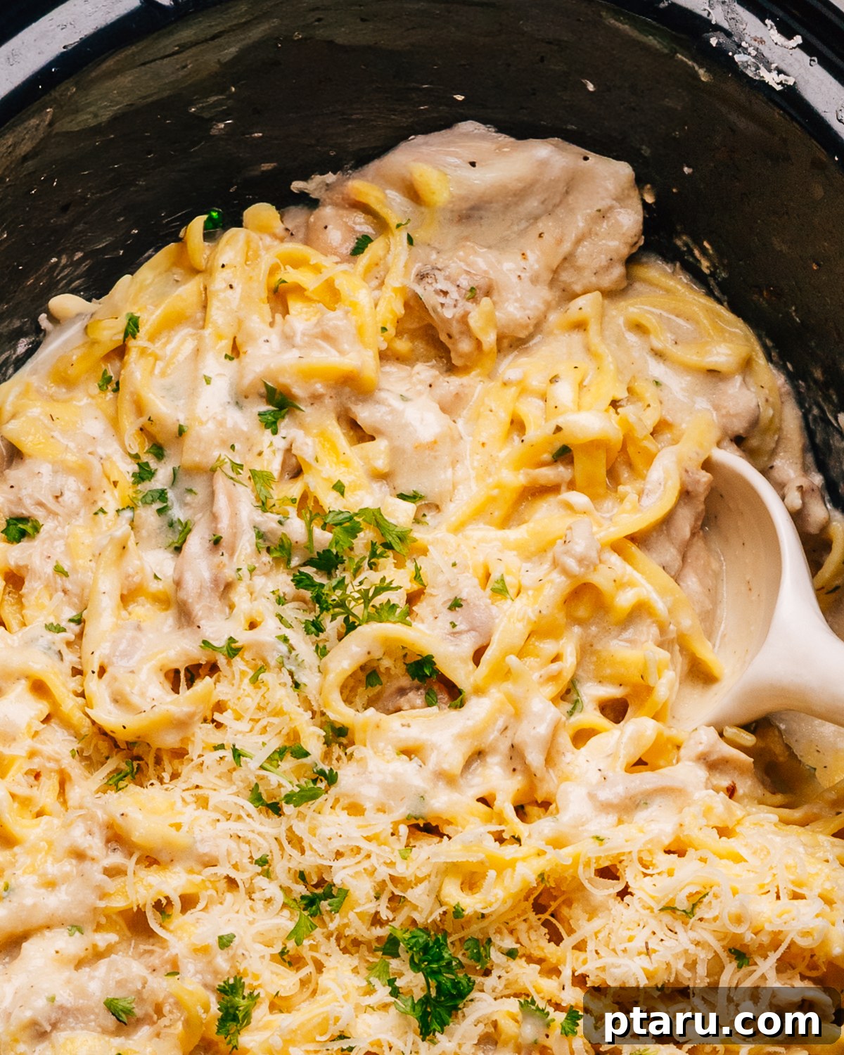 Creamy Slow Cooker Chicken Alfredo 10 Close up shot of creamy Crockpot Chicken Alfredo recipe with a spoon, highlighting the rich sauce and tender chicken.