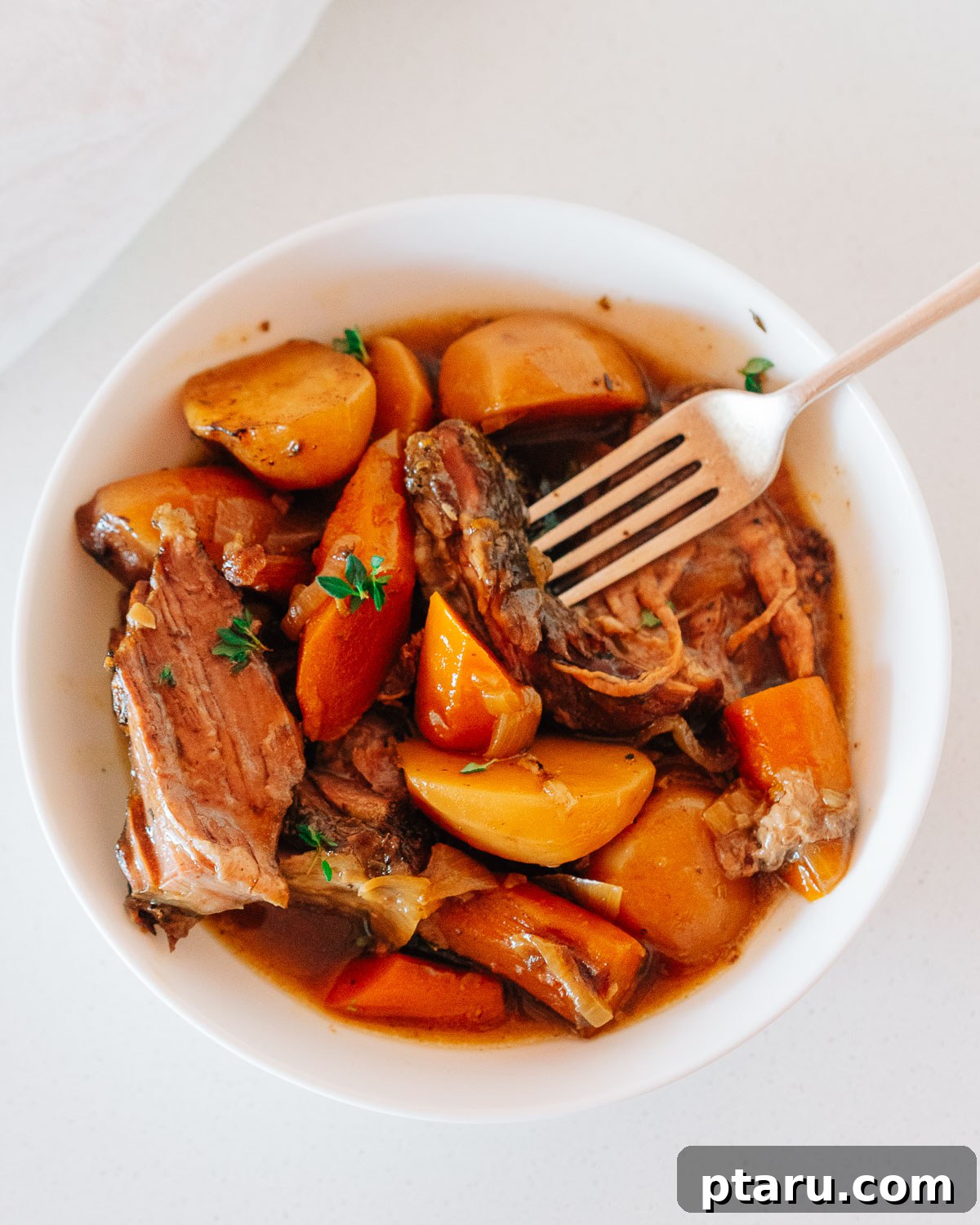 Slow Cooker Chuck Roast Melts in Your Mouth 9 Close-up of a serving of Crock Pot Chuck Roast with tender beef, gravy, carrots, and potatoes.