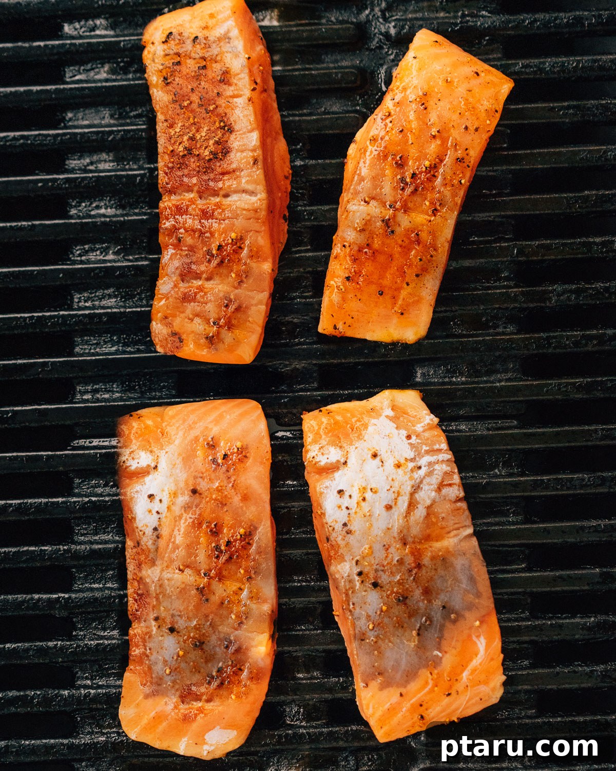 Succulent Grilled Salmon 6 Pieces of salmon on grill grates.
