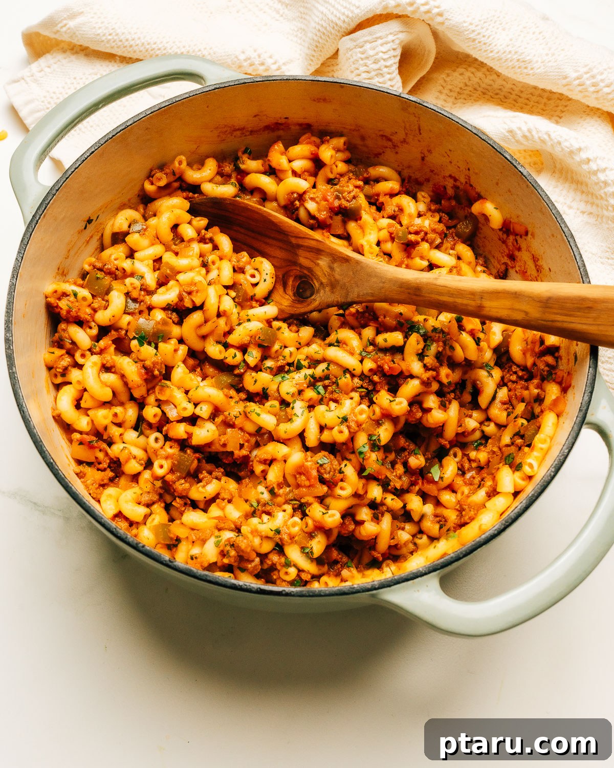 Classic Macaroni Goulash 2 A large pot filled with a steaming, rich American Chop Suey, featuring ground beef, elbow macaroni, and a luscious tomato sauce, with a wooden spoon resting inside.
