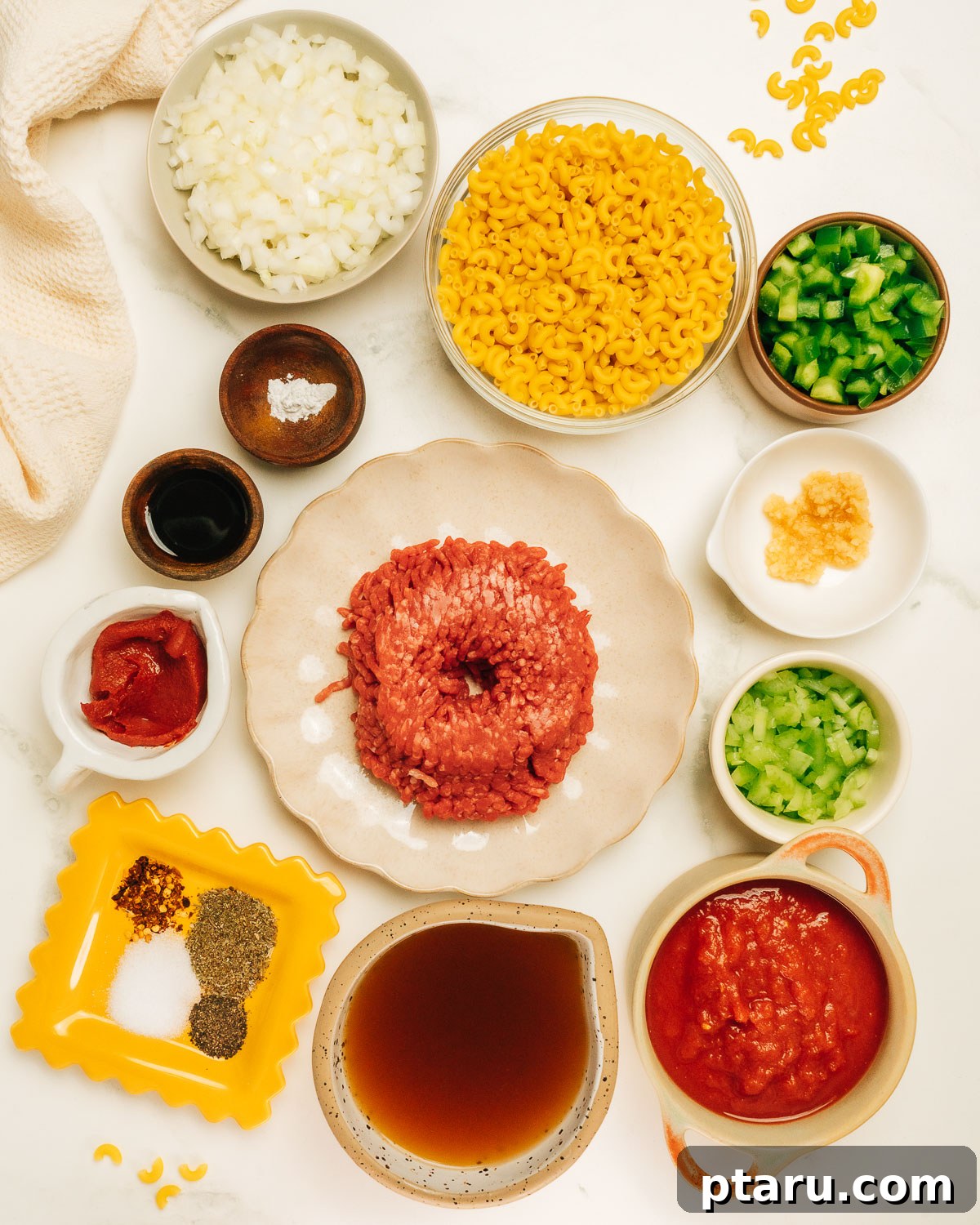 Classic Macaroni Goulash 3 A counter displaying all the fresh ingredients needed for American Chop Suey, including ground beef, elbow macaroni, onions, bell peppers, tomatoes, and various spices.