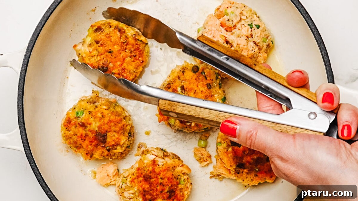Frying Crispy Salmon Patties Frying six salmon patties in a skillet with oil.
