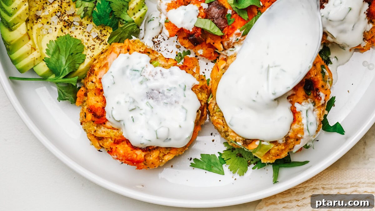 Serving Salmon Patties with Dill Sauce and Salad Golden salmon patties served on a white plate with a side salad and a bowl of creamy dill sauce.