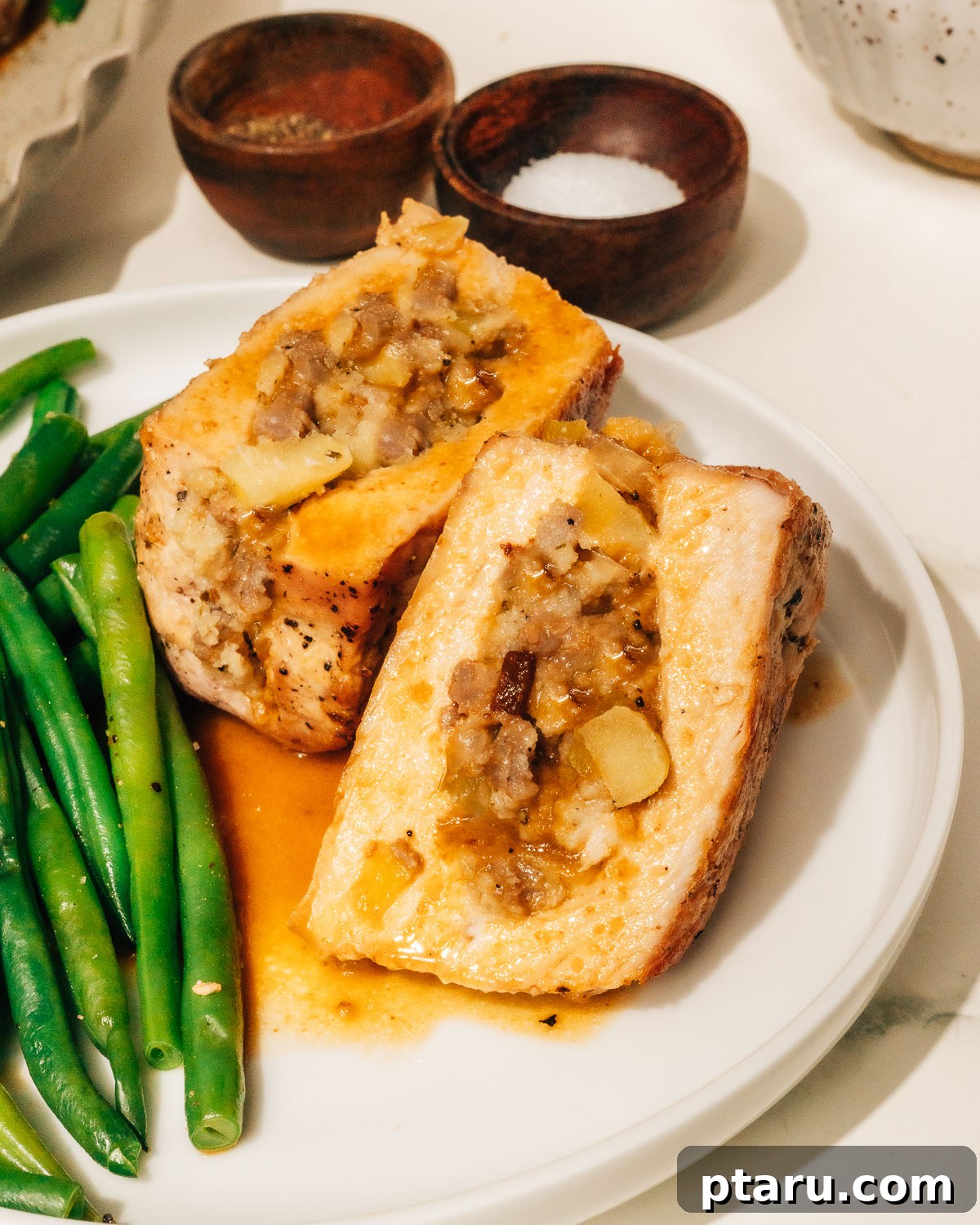 Juicy Stuffed Pork Chops with Luscious Pan Sauce 10 A perfectly cooked stuffed pork chop, sliced in half to reveal the succulent pork and the rich, flavorful apple and sausage stuffing, ready to be enjoyed.